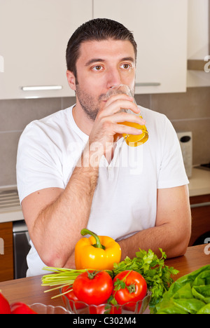 Mid adult man de boire du jus d'orange dans la cuisine Banque D'Images