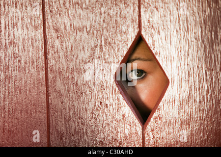 Une femme se profile au trou en forme de diamant dans un mur. Plan horizontal. Banque D'Images