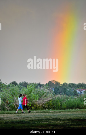 Femmes marchant avec arc-en-ciel sur park Banque D'Images