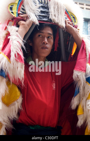 Un homme asiatique porte un costume dragon coloré tout en célébrant le Nouvel An chinois au Cambodge. Banque D'Images
