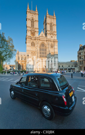 L'Abbaye de Westminster illuminé par le soleil couchant, à Londres, Angleterre, Royaume-Uni. Avec London Taxi driving passé. Banque D'Images