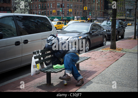 Un sans-abri dormant sur un banc de parc dans le lower Manhattan à New York, le vendredi 22 avril 2011. (© Frances M. Roberts) Banque D'Images