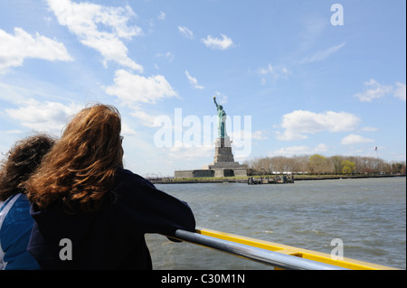 Les touristes les croisières à bord d'un port de New York New York Water Taxi regardez la Statue de la liberté sur une île dans la rivière Hudson. Banque D'Images