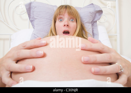 Pregnant woman in bed sentiment contractions. Banque D'Images