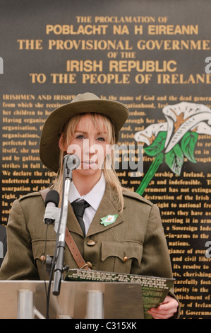 Belfast, Irlande du Nord. 24 avr 2011 - Femme vêtue d'un uniforme de l'Armée républicaine de 1920 lit la proclamation comme irlandais Sinn Fein commémorer le soulèvement de Pâques 1916 Banque D'Images