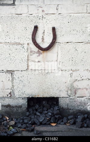 Horseshoe verticale invitant bonne chance, placé sur un bunker du charbon dans le jardin d'une maison de Northumberland, en Angleterre, UK. Banque D'Images