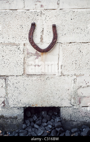 Horseshoe verticale invitant bonne chance, placé sur un bunker du charbon dans le jardin d'une maison de Northumberland, en Angleterre, UK. Banque D'Images