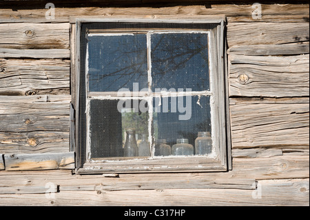 Pionnier américain, cabane en bois taillées à la main, avec de vieilles bouteilles sur le rebord de la fenêtre à Ancho, Nouveau Mexique. Banque D'Images