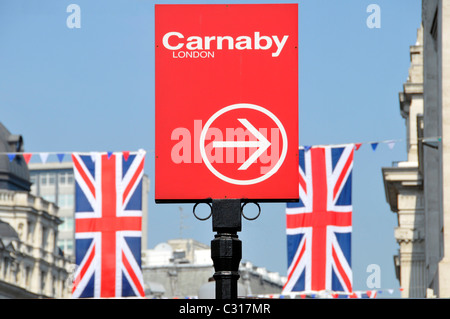 Scène de rue à Londres red Carnaby Street sign & flèche pointant à la mise hors tension du côté de Regent Street où l'Union Jack drapeaux sont tendus en travers de la route UK Banque D'Images