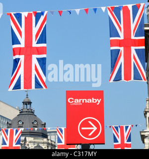 Panneau rouge et flèche indiquant la célèbre rue Carnaby À l'extrémité ouest de Londres avec Union Jack Flags Union Drapeau avec couuntage bleu ciel Angleterre Royaume-Uni Banque D'Images