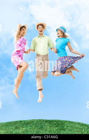 Portrait of joyful in jump holding homme heureux par la main de ciel bleu sur l'arrière-plan Banque D'Images