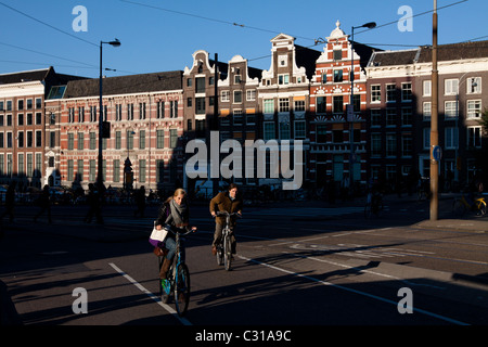 Les cyclistes en face de bâtiments typiquement Néerlandais à Amsterdam Banque D'Images