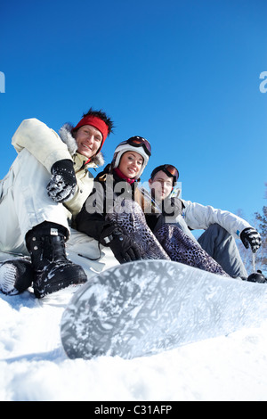 Portrait of happy company de gars et girl sitting on snow Banque D'Images