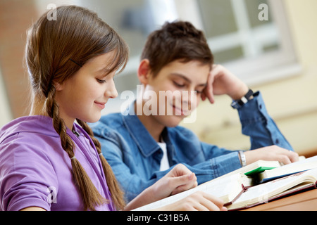 Portrait of teenage girl reading book avec son condisciple à l'arrière-plan Banque D'Images