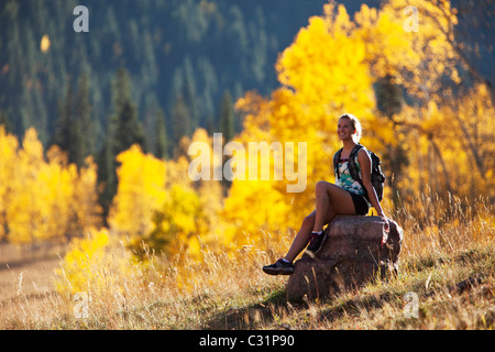 Une jeune femme s'arrête de randonnée et jouit de la beauté des couleurs de l'automne doré. Banque D'Images