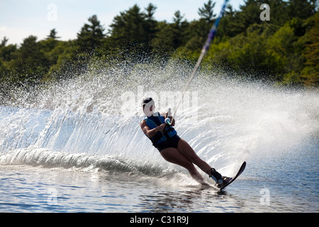 Une skieuse nautique déchire tour provoquant un énorme jet d'eau tandis que le ski sur le lac Cobbosseecontee près de Monmouth, Maine. Banque D'Images