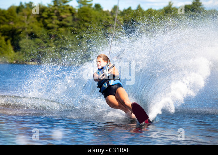 Une skieuse nautique déchire tour provoquant un énorme jet d'eau tandis que le ski sur le lac Cobbosseecontee près de Monmouth, Maine. Banque D'Images