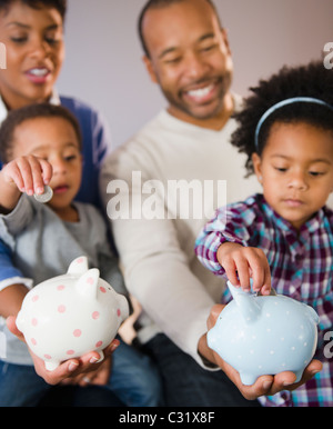 Black parents enfants mettre de l'argent à piggy bank Banque D'Images