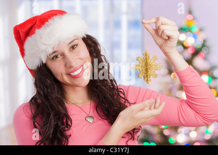 Mixed Race woman holding Christmas ornament Banque D'Images