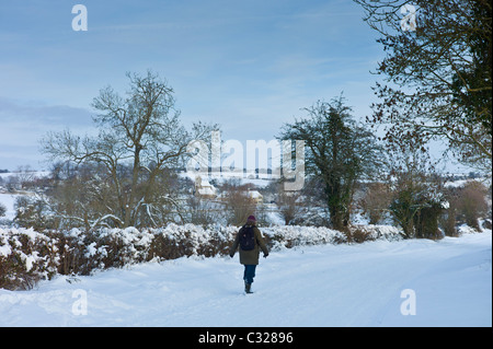 Lone walker le long couloir couvert de neige dans la vallée, Windrush, les Cotswolds Swinbrook Banque D'Images
