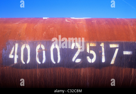 Grand tube de métal avec surface légèrement rouillé et la création d'un numéro de lot inscrit sur elle couché sous ciel bleu Banque D'Images