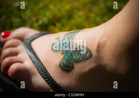 Tatouage papillon sur un pied de femme jeune Banque D'Images