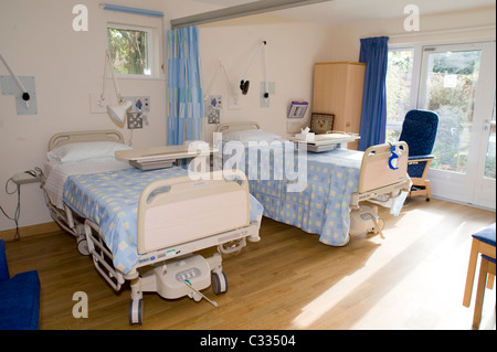 Deux lits d'hôpital dans un hospice avec le soleil qui brille à l'intérieur et de grandes fenêtres Banque D'Images