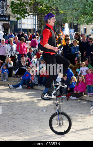 Artiste de rue sur un monocycle avec des torches enflammées devant une foule au Royaume-Uni Banque D'Images