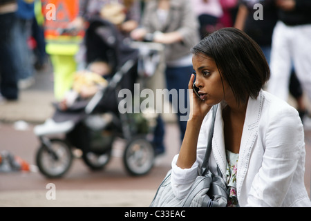 Jeune jolie teen Latina black girl femme assise dans la rue avec un téléphone mobile appelant portant veste blanche en été Rotterdam Banque D'Images