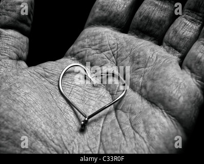 La forme ou symbole d'un coeur dans la main d'un vieux pêcheur... Banque D'Images