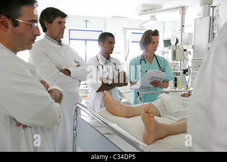 Médecins et infirmières examining patient dans un lit d'hôpital Banque D'Images