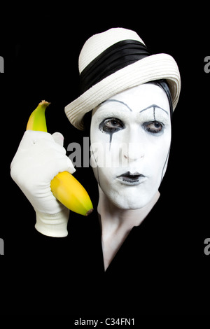 Portraits de la mime dans white hat holding une banane dans sa main Banque D'Images