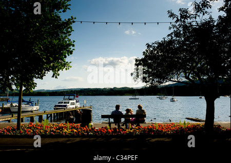 Vue arrière des personnes silhouetées assis sur un banc en bois donnant sur le lac Windermere, Cumbria, Royaume-Uni Banque D'Images