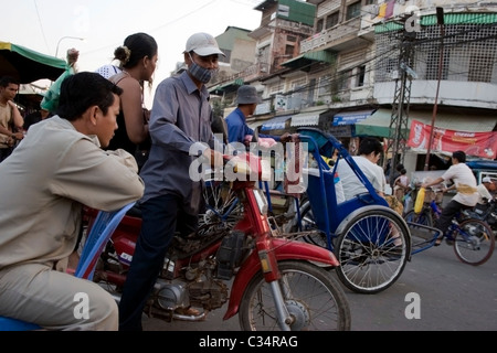 Un chauffeur de taxi moto est prise d'une passagère à proximité d'un marché très fréquenté sur une rue de ville de Phnom Penh, Cambodge. Banque D'Images