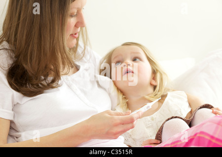 Contrôle de la mère de sa fille, fièvre avec thermomètre numérique Banque D'Images