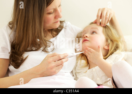 Contrôle de la mère de sa fille, fièvre avec thermomètre numérique Banque D'Images