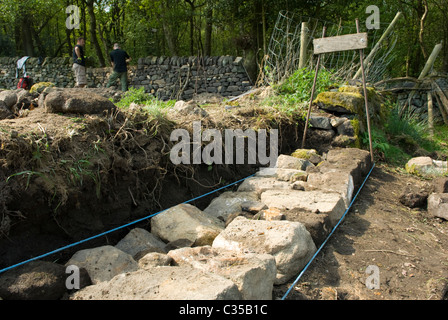 Un passage de mur en pierre sèche en cours de reconstruction, montrant des pierres de fondation. Banque D'Images