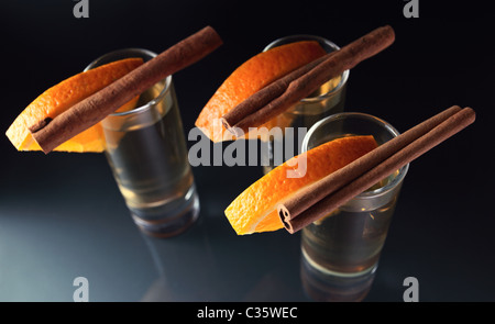 Tequila avec orange et cannelle sur une table en verre. Banque D'Images