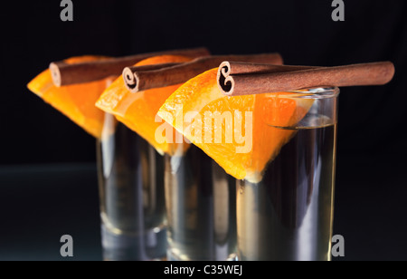 Tequila avec orange et cannelle sur une table en verre. Banque D'Images