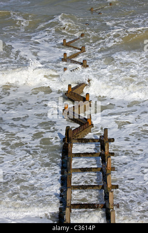 Les vagues se brisant au-dessus d’un brise-lames en bois, les groynes font partie des défenses côtières de la Grande-Bretagne. Banque D'Images