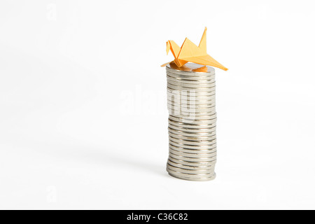 Pile de pièces d'argent et de l'origami bird jaune isolé sur fond blanc Banque D'Images