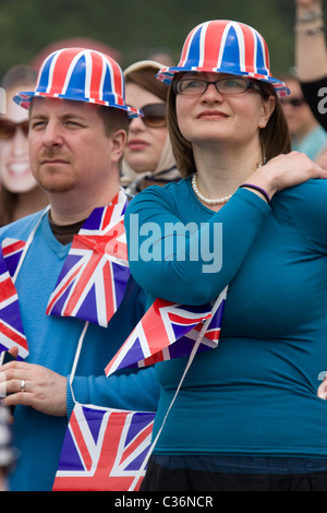 Les fêtards royaux de mariage célèbrent avec des chapeaux et des drapeaux union Jack regardant des écrans géants diffusant mariage à Hyde Park, Londres, Royaume-Uni Banque D'Images