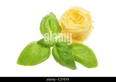 Feuilles d'herbe de basilic frais et d'un nid de pâtes séchées tagliatelli isolés contre white Banque D'Images