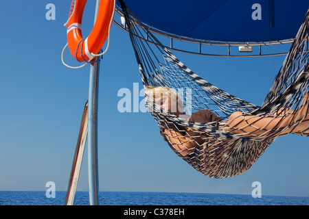 Boy resting in hammock on yacht Banque D'Images