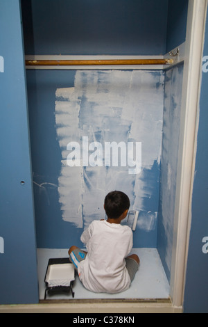 Boy painting wall en penderie Banque D'Images