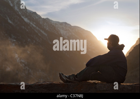 Un jeune homme se détendre et admirer le coucher du soleil à La Grave, France Banque D'Images