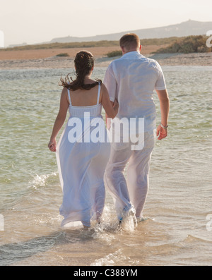 Jeune couple nouvellement marié à marcher ensemble sur une plage tropicale Banque D'Images