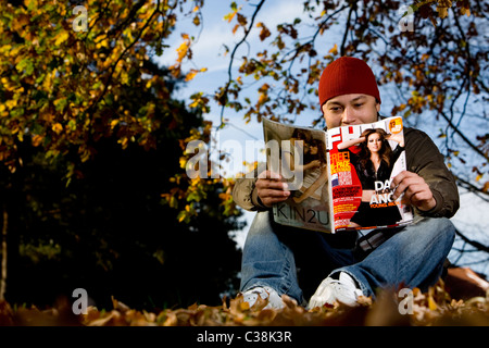 Un homme la lecture d'une copie du magazine FHM. Banque D'Images