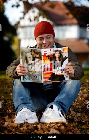 Un homme la lecture d'une copie du magazine FHM. Banque D'Images