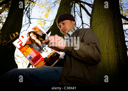 Un homme la lecture d'une copie du magazine FHM. Banque D'Images